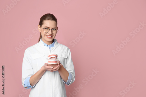 Female dentist holding jaws model on color background. Space for text