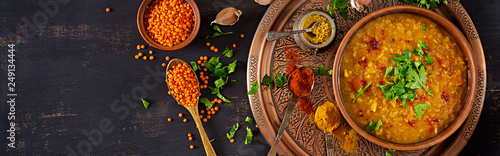 Indian dal. Food. Traditional Indian soup lentils. Indian Dhal spicy curry in bowl, spices, herbs, rustic black wooden background. Top view. Authentic Indian dish. Banner. Flat lay