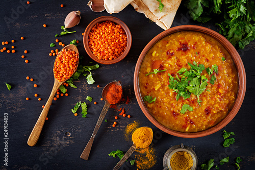 Indian dal. Food. Traditional Indian soup lentils. Indian Dhal spicy curry in bowl, spices, herbs, rustic black wooden background. Top view. Authentic Indian dish. Overhead. Flat lay