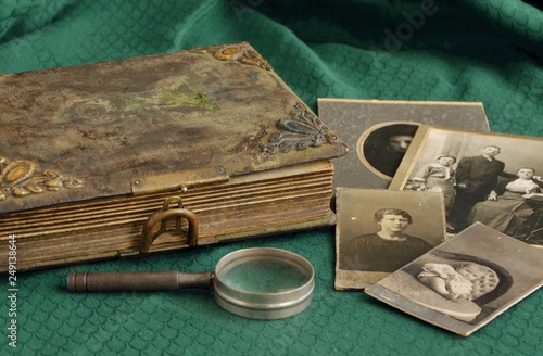 Old photo album and historical photos of family on a green tablecloth.