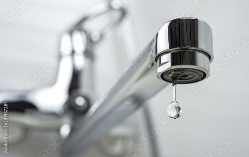 A drop of pure water dripping from the tap. Selective focus.