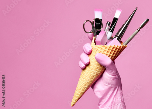 Manicure and pedicure abstract concept. Hand hold waffles cone with instruments for nails salon and spa brush nail file 