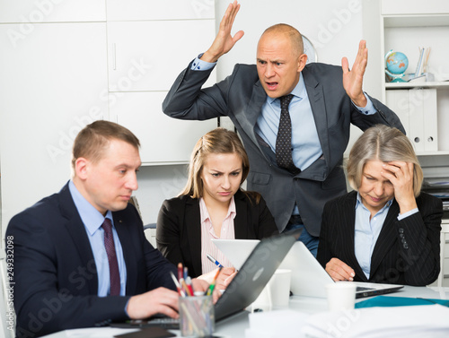 Group of sad frustrated employees receiving rebuke, suffering from bad attitude of shouting executive at work