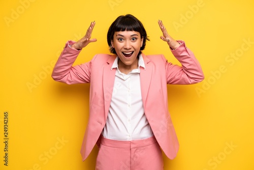 Modern woman with pink business suit with surprise and shocked facial expression
