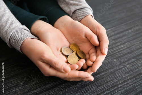 Hands of woman and his son holding coins on wooden table. Concept of child support