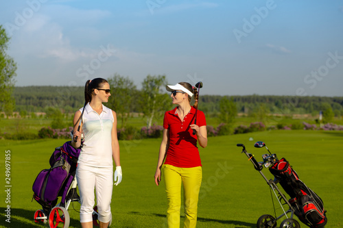 Two pretty women golfers walking at golf course