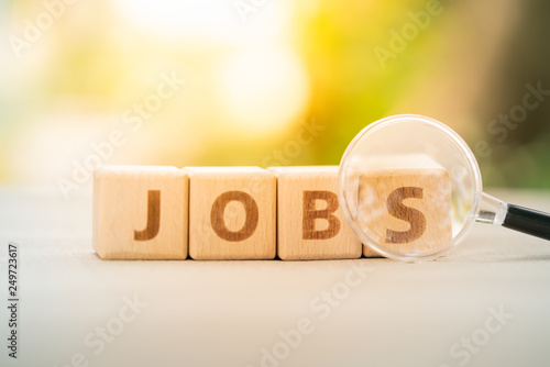 Wood block word JOB and magnifying glass with copy space using as background Choice of the best suited employee, HR, HRM, HRD, job recruiter concepts.