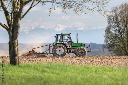 bauer sitzt auf traktor und fährt mit einer egge