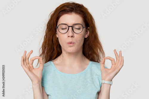 Stressed redhead woman meditating relieving stress doing breathing exercises