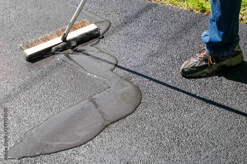 Spreading asphalt resealer onto driveway for maintenance