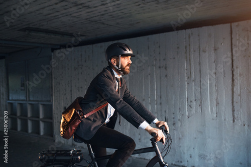 Hipster businessman commuter with electric bicycle traveling to work in city.