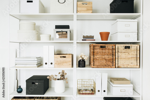 Modern home office cabinet interior design concept. White storage shelves with boxes, eucalyptus, decorations. Scandinavian style room.