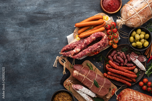 Assortment of Sausage and ham . Assorted meat products, including smoked sausages, ham and salami with vegetables and spices