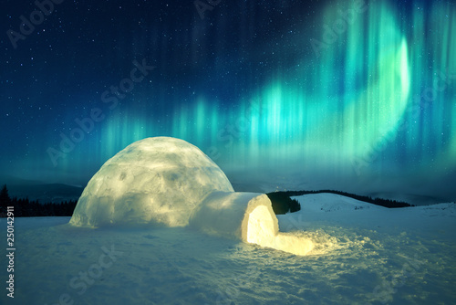 Aurora borealis. Northern lights in winter mountains. Wintry scene with glowing polar lights and snowy igloo