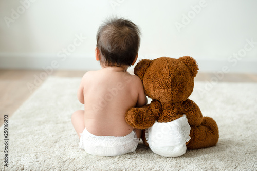 Back of a baby with a teddy bear