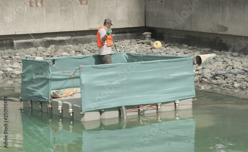 Worker removes debris and floating vegetation from the lake