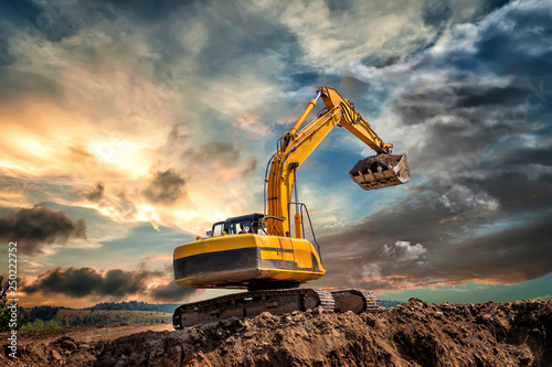 Crawler excavator during earthmoving works on construction site at sunset