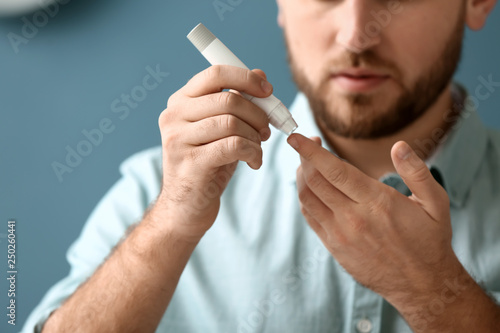 Diabetic man taking blood sample with lancet pen at home