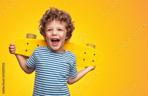 Bright curly boy with colorful longboard 