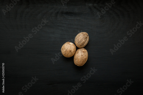 Close-up image of nutmeg on black wood background, view above