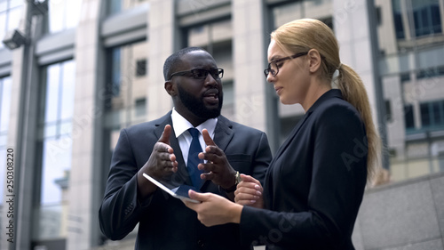 Client convincing lady investor of project profitability, shows income on tablet