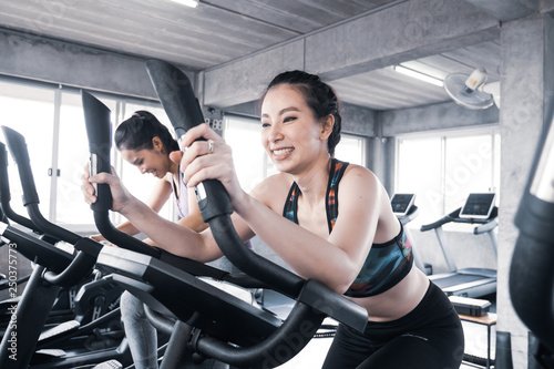 Attractive young women working out together on exercise bike at the gym.