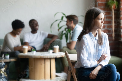 Girl outcast sits apart from peers in cafeteria