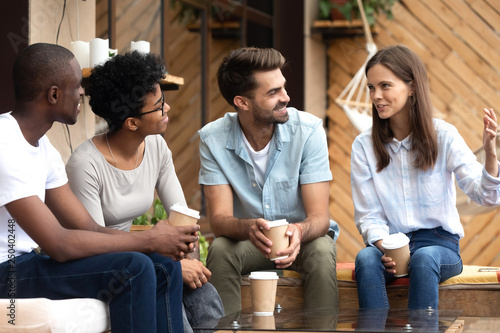 Friend listening to girl sitting together in cafe drinking coffee