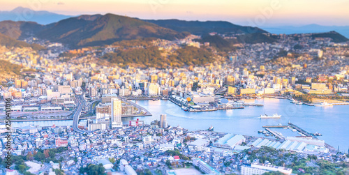 Business concept, tilt shift effect modern cityscape of nagasaki dusk from mount inasa, the new top 3 nightview of the world, aerial view, copy space