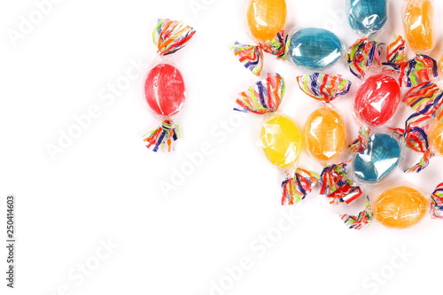Colorful hard candies in transparent cellophane wrapping, isolated on white background, top view