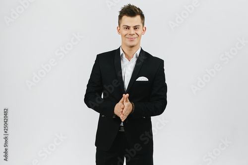 Fashionable and handsome young emotional man in white shirt and in stylish black suit isolated at white background