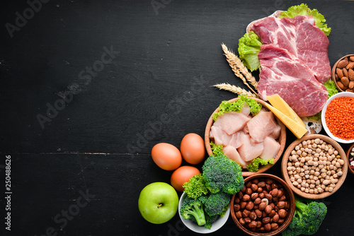 High protein food. Healthy nutrition or diet concept. Meat, chicken fillet, broccoli, beans, cheese, eggs, wheat. On a black background.