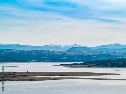 Landscape of a reservoir and mountains in a day with fog and clouds and birds swimming and flying in in La Maya Reservoir (Salamanca)