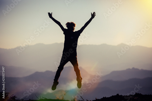black silhouette of man in happy jump on sunset sky and mountain background