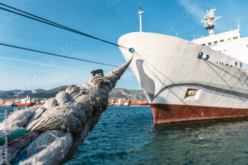 White big ship moored in harbour port, selective focus on mooring rope