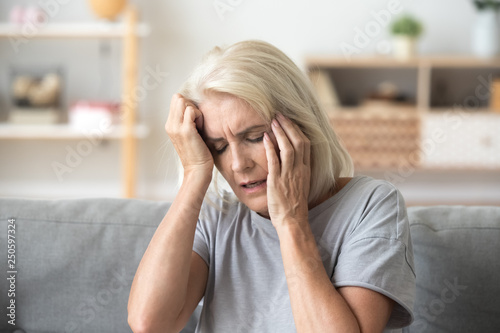 Close up aged woman suffering from headache, touching head