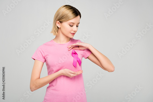 cropped view of beautiful blonde woman posing in pink t-shirt with breast cancer awareness ribbon, isolated on grey