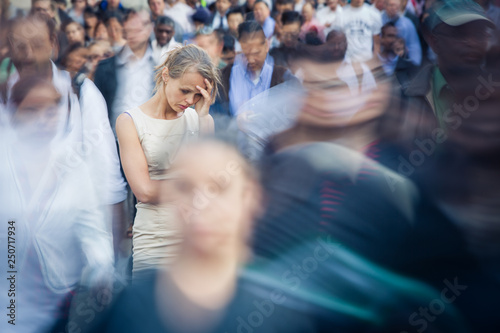 Depressed young woman feeling alone amid a crowd of people in a big city