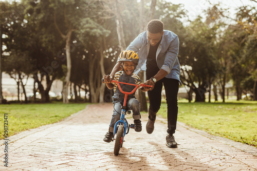 Father teaching his son cycling at park