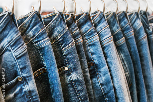 many models of jeans from different denim, texture, color hang on hangers