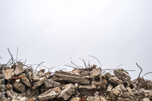 The rebar sticking up from piles of brick rubble, stone and concrete rubble against the sky in a haze.