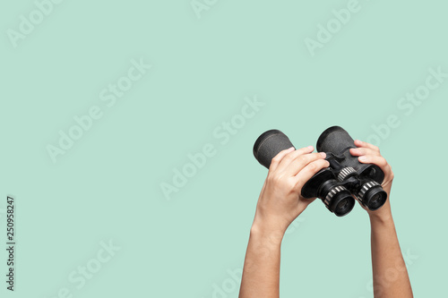 Hands holding binoculars on green background