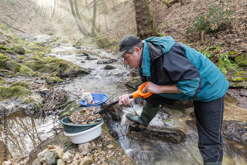 Adventures on river. Gold prospector is filling a sieve with sand