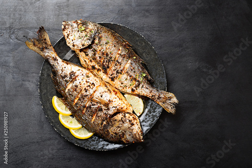 Tasty grilled fish dorado with lemon on kitchen table.