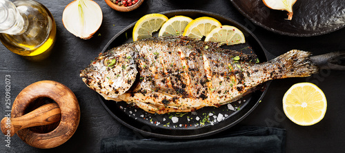 Tasty grilled fish dorado with lemon on kitchen table.