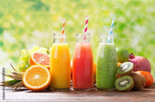 bottles of fruit juice and smoothie with fresh fruits