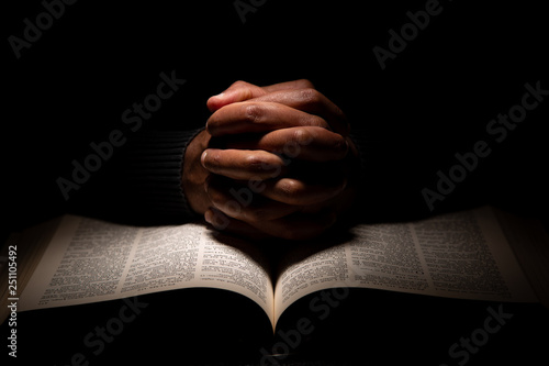 African American Man Praying with Hands on Top of the Bible.