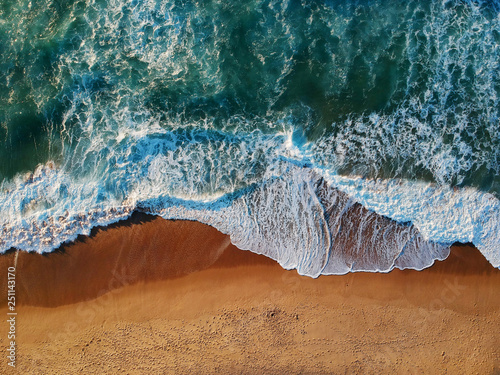 Aerial view of sandy beach with waves and clear ocean water. Drone photo