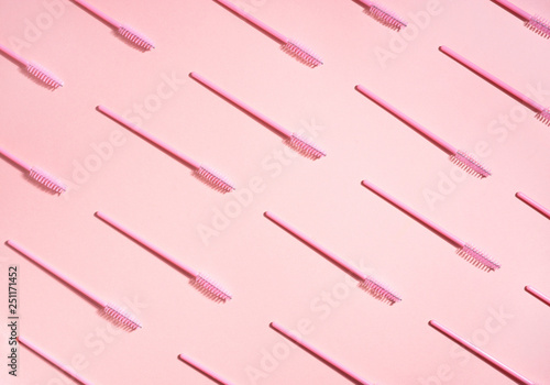 Creative concept beauty photo of lashes extensions brush on pink background.