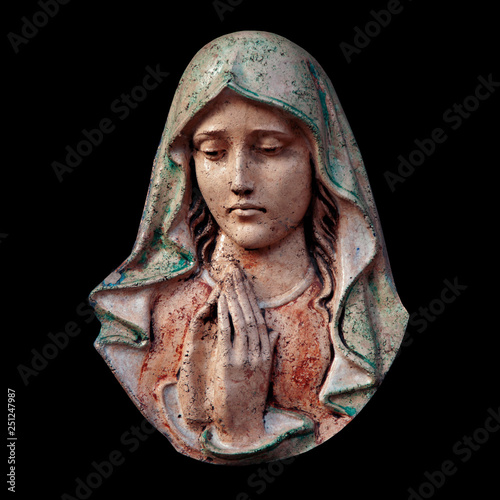Antique statue of Virgin Mary against black background.